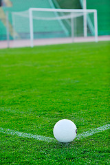 Image showing Soccer ball on grass at goal and stadium in background