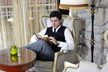 Image showing young man reading book and relaxing in luxury indoor