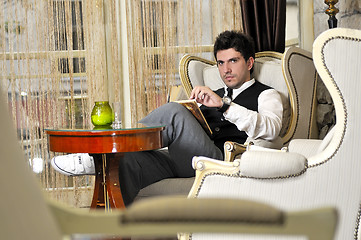 Image showing young man reading book and relaxing in luxury indoor