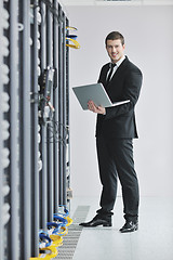 Image showing businessman with laptop in network server room