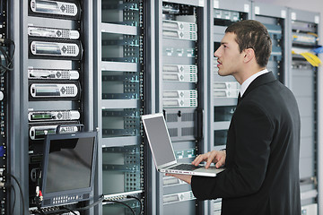 Image showing businessman with laptop in network server room