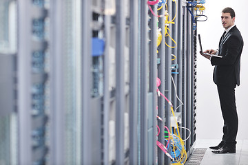 Image showing businessman with laptop in network server room