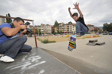 Image showing Man taking photo of boy skating in park