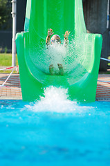 Image showing girl have fun  on water slide at outdoor swimming pool