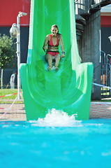 Image showing girl have fun  on water slide at outdoor swimming pool