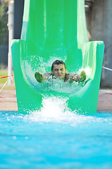 Image showing girl have fun  on water slide at outdoor swimming pool