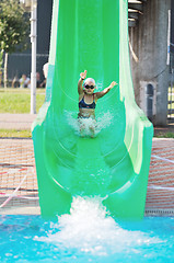 Image showing girl have fun  on water slide at outdoor swimming pool