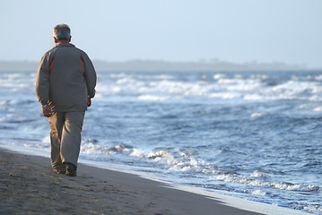 Image showing lonely older  man walking on beach