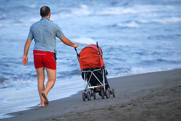 Image showing father with stroller at early morning walking on beach