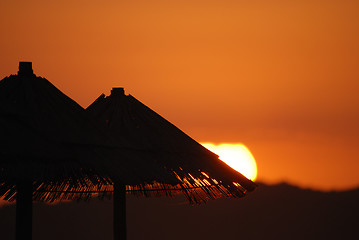 Image showing sunshine on beach with beach umbrellas silhouette