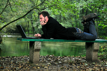 Image showing young businessman working on laptop outdoor