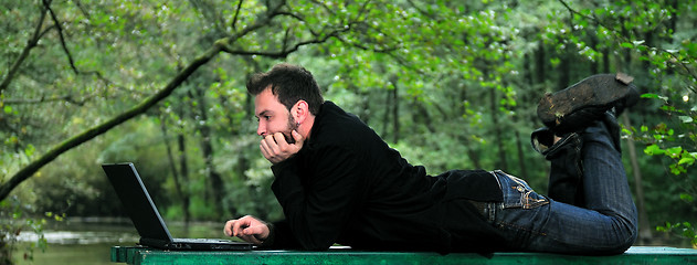 Image showing young businessman working on laptop outdoor