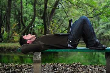 Image showing young businessman working on laptop outdoor