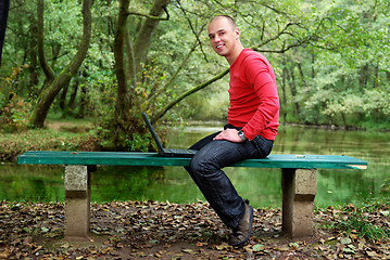 Image showing young businessman in red shirt working on laptop 