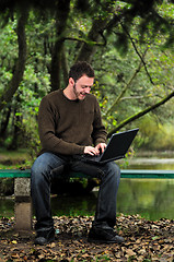 Image showing young businessman working on laptop outdoor