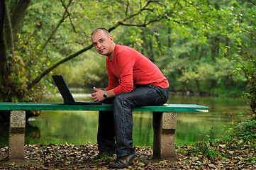 Image showing young businessman in red shirt working on laptop 