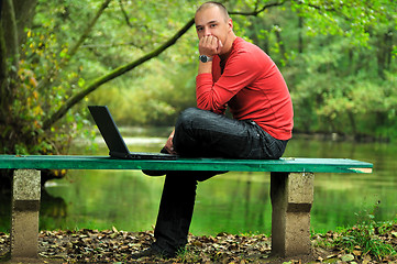 Image showing young businessman in red shirt working on laptop 