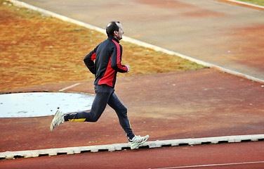 Image showing adult man running on athletics track