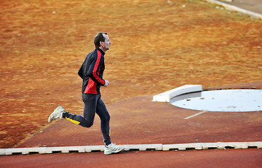 Image showing adult man running on athletics track