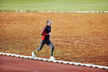 Image showing adult man running on athletics track