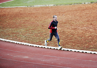 Image showing adult man running on athletics track