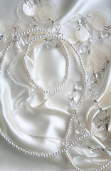 Image showing White pearls and nacreous beeds on white silk as wedding backgro