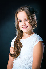 Image showing cute girl in white lacy dress and black hat on dark background