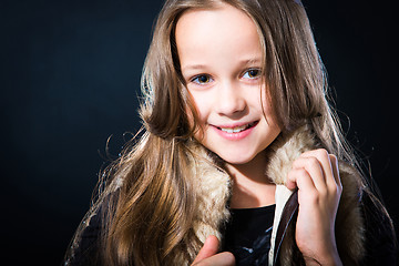 Image showing  girl with fair long hair in fur vest on dark background