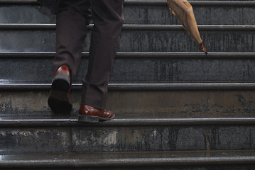 Image showing business executive climbing up stairs with umbrela in his hand