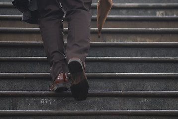 Image showing business executive climbing up stairs with umbrela in his hand