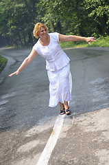 Image showing middle age woman walk on white line on road outdoor