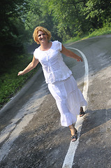 Image showing middle age woman walk on white line on road outdoor