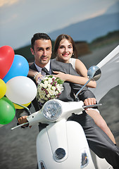 Image showing just married couple on the beach ride white scooter