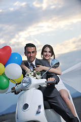 Image showing just married couple on the beach ride white scooter