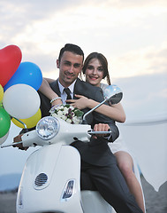 Image showing just married couple on the beach ride white scooter