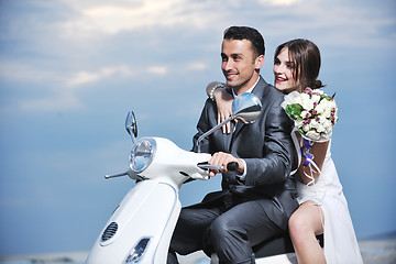 Image showing just married couple on the beach ride white scooter