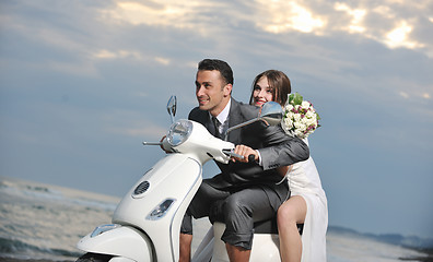 Image showing just married couple on the beach ride white scooter