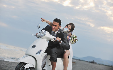 Image showing just married couple on the beach ride white scooter