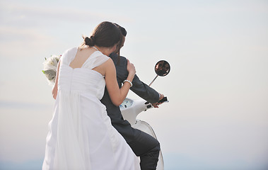 Image showing just married couple on the beach ride white scooter