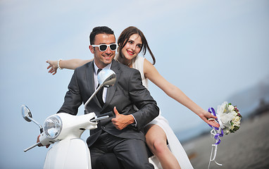 Image showing just married couple on the beach ride white scooter