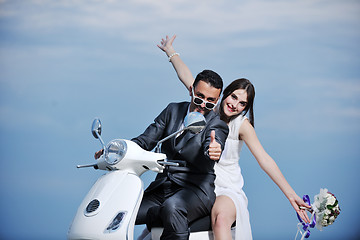 Image showing just married couple on the beach ride white scooter