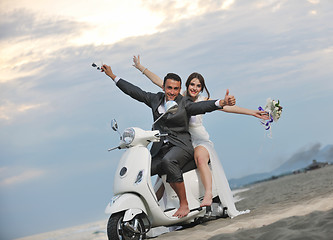 Image showing just married couple on the beach ride white scooter