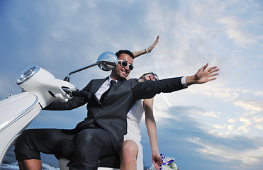 Image showing just married couple on the beach ride white scooter