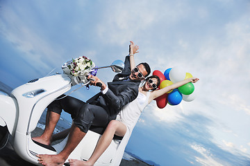 Image showing just married couple on the beach ride white scooter