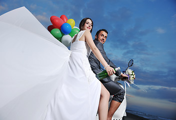 Image showing just married couple on the beach ride white scooter