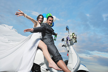 Image showing just married couple on the beach ride white scooter