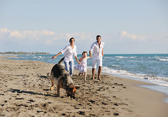 Image showing happy family playing with dog on beach