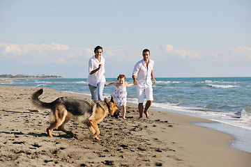 Image showing happy family playing with dog on beach