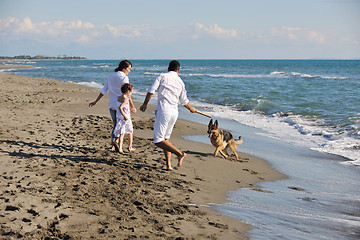 Image showing happy family playing with dog on beach