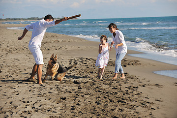 Image showing happy family playing with dog on beach